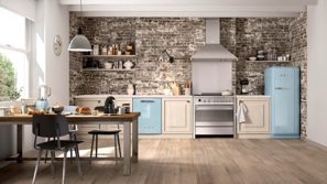 Farmstyle kitchen with cream cabinetry, blue fridge, brick wall and wooden dining table