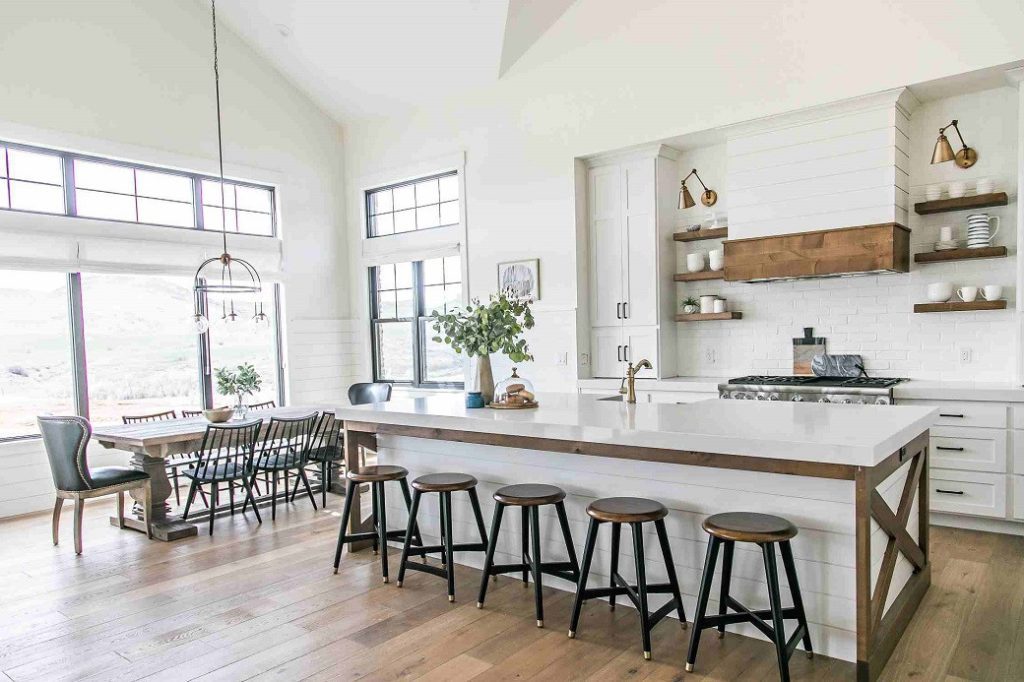 Bright farmstyle kitchen with large island, wooden stools and dining table