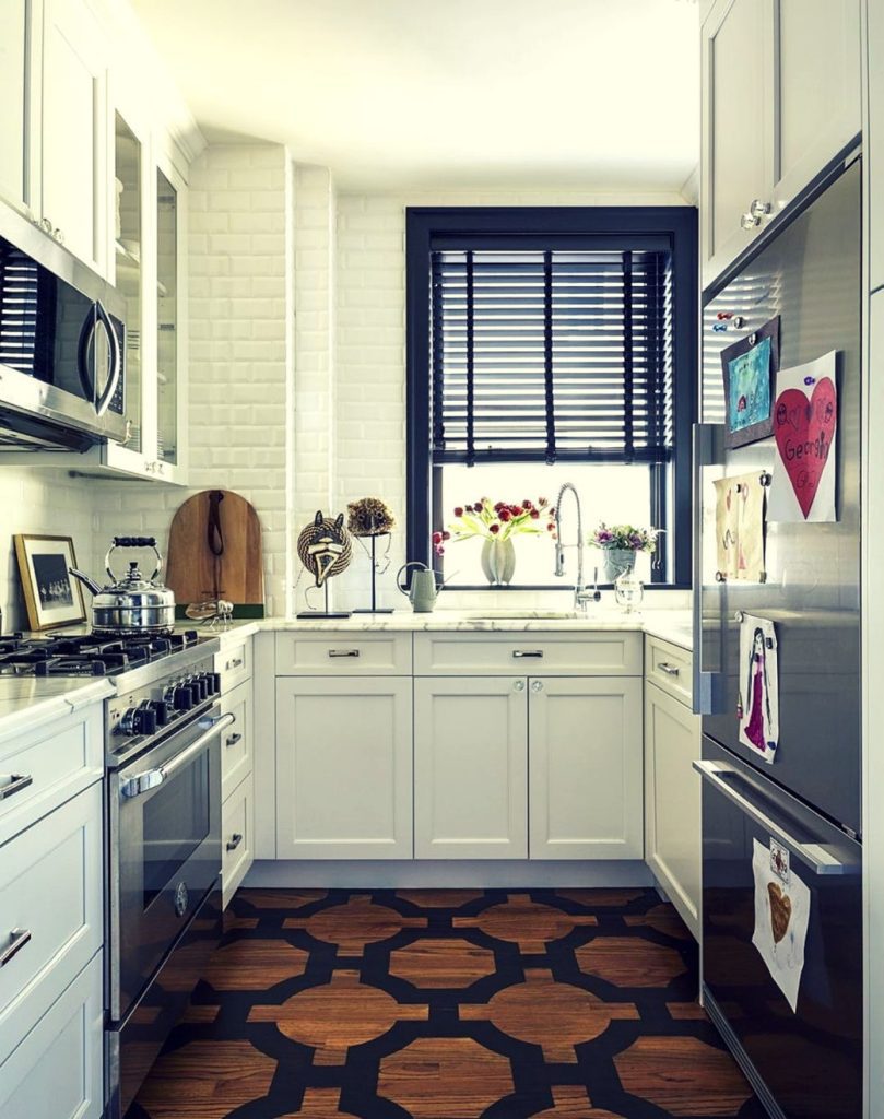 Compact kitchen with white cabinetry, stainless steel appliances, and patterned wooden floor