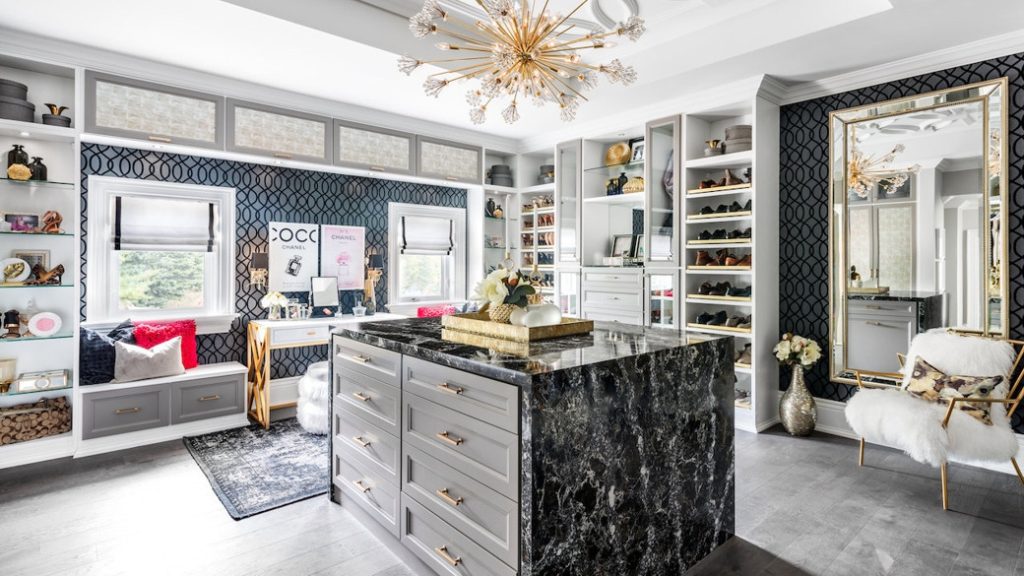 Spacious walk-in closet with central island, shelving, and seating area