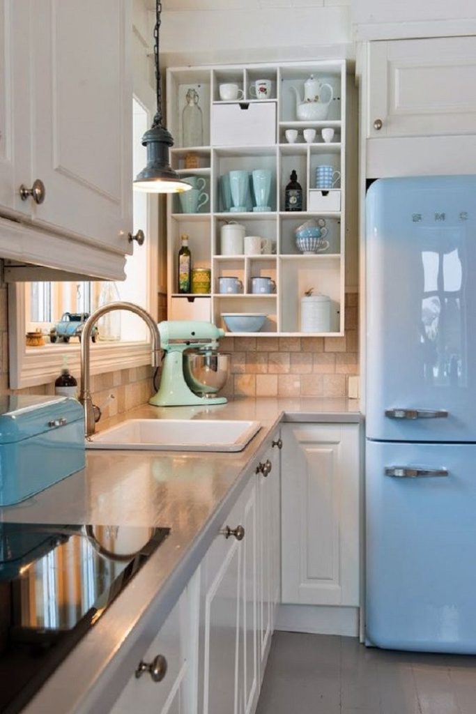 Modern kitchen with white cabinetry, blue retro fridge, and open shelving with crockery