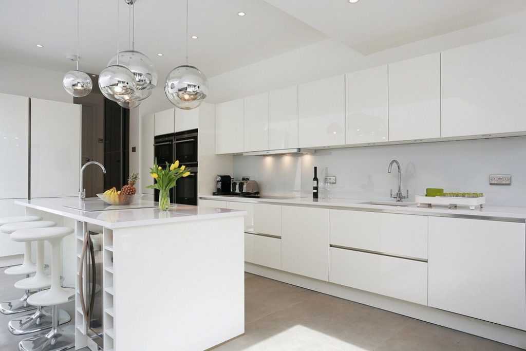 Bright kitchen with white cabinetry, island, bar stools and chrome pendant lights