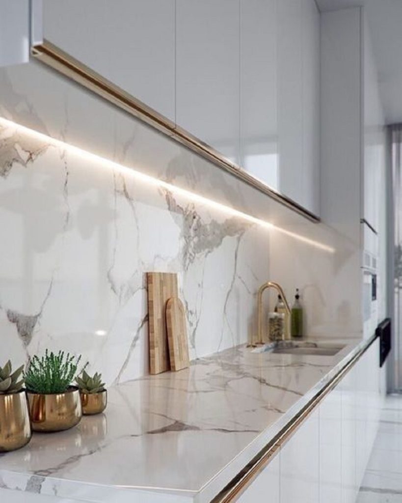 Kitchen countertop and backsplash with integrated LED strip lighting and gold-tone fixtures