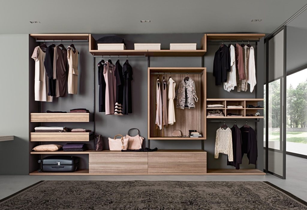Open fitted wardrobes with hanging clothes, shelves, drawers and handbags in neutral tones