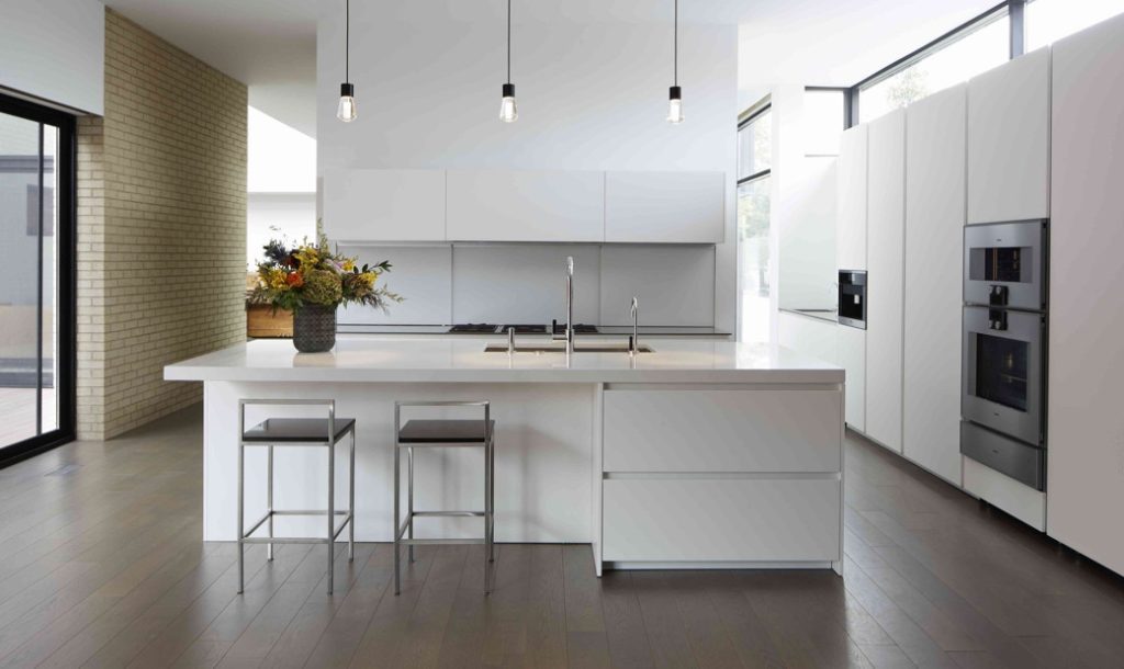 Bright kitchen with white cabinetry, central island, two stools and pendant lights