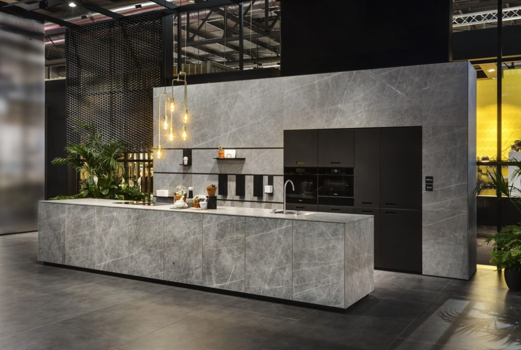 Kitchen with grey stone-effect cabinetry and black built-in appliances under hanging pendant lights