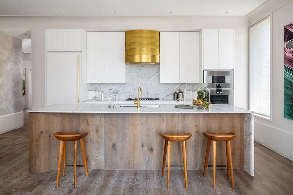 Kitchen with white cabinetry, stone countertop, wooden island front and three wooden stools