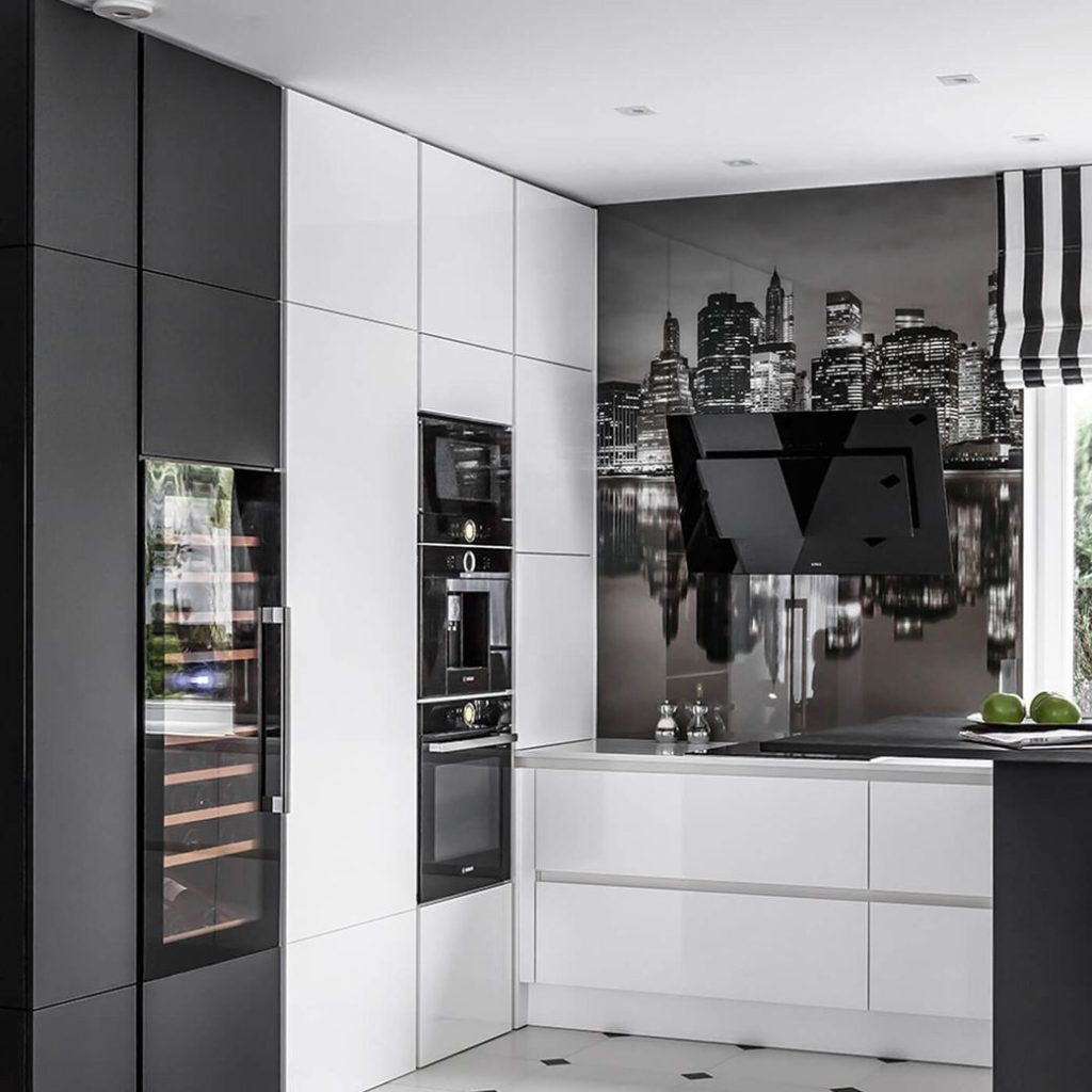 Black and white fitted kitchen with built-in appliances and cityscape backsplash