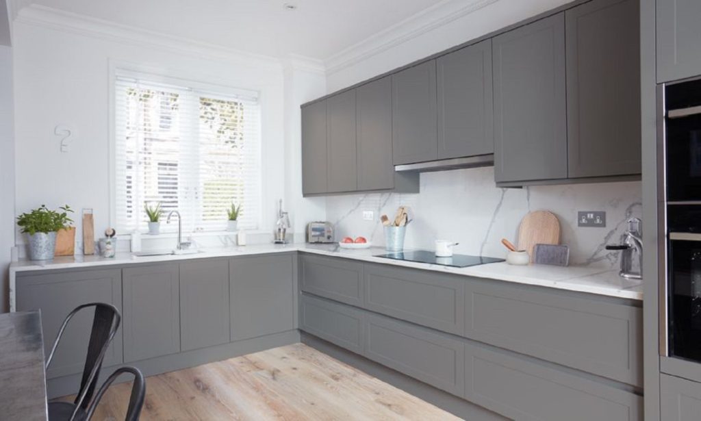 Bright kitchen with grey cabinetry, white stone-effect countertops and wooden floor