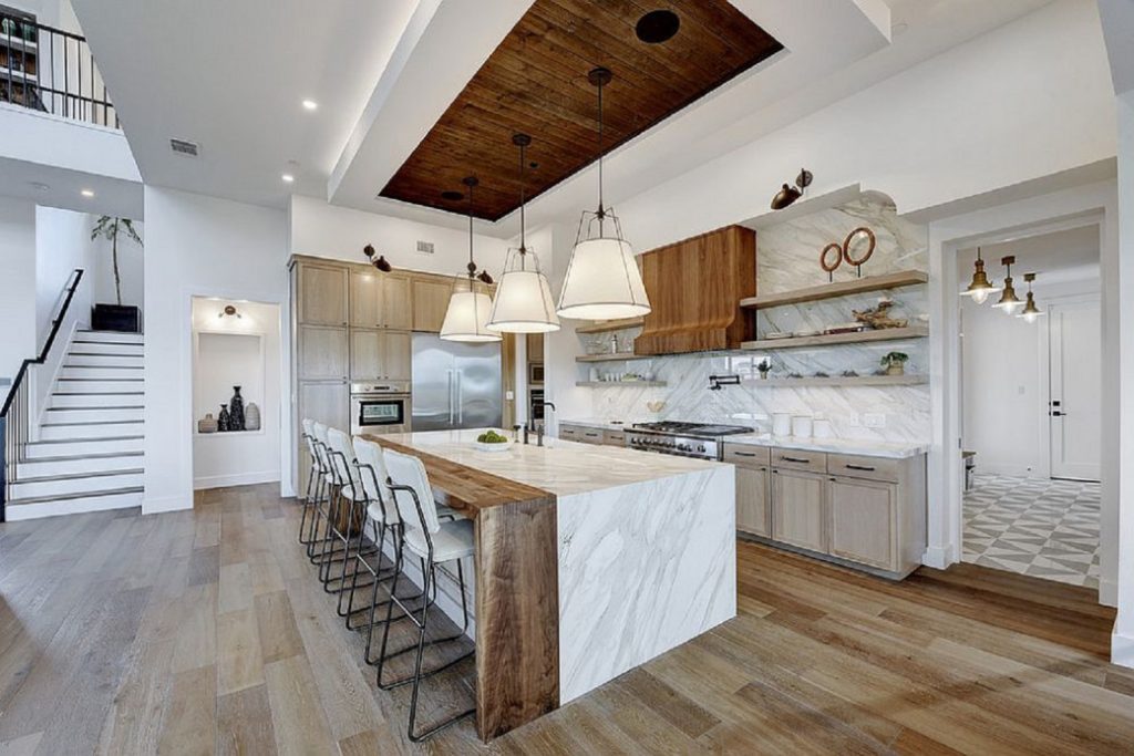 Spacious kitchen with large stone island and wooden accents under pendant lights