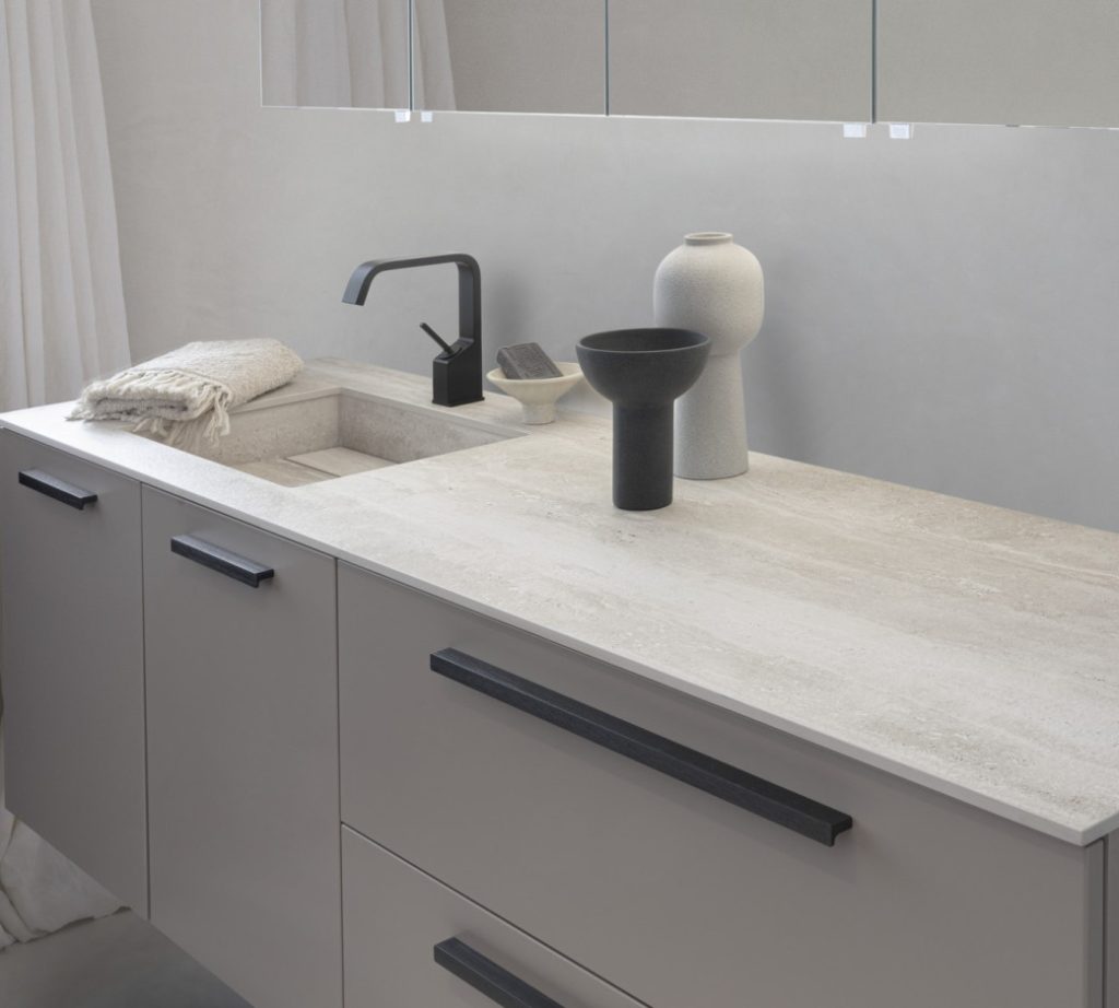 Light grey kitchen vanity with integrated sink, black faucet and decorative vases on countertop