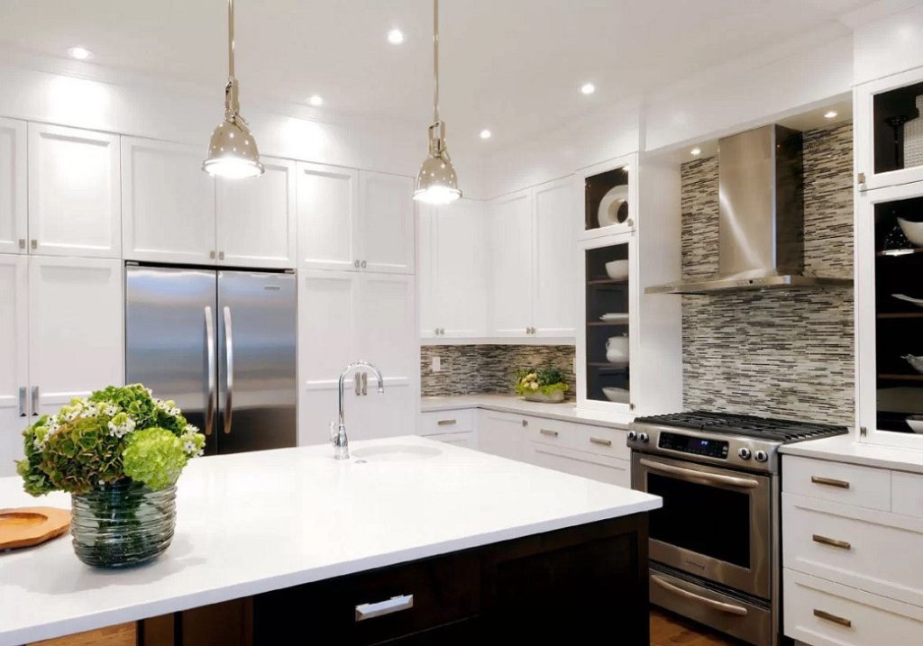 Bright kitchen with white cabinetry, stainless steel appliances, and a central island with a sink