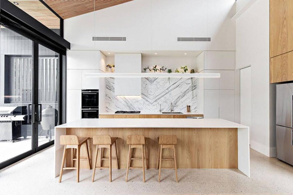 Bright contemporary kitchen with white island and wooden stools under wooden ceiling