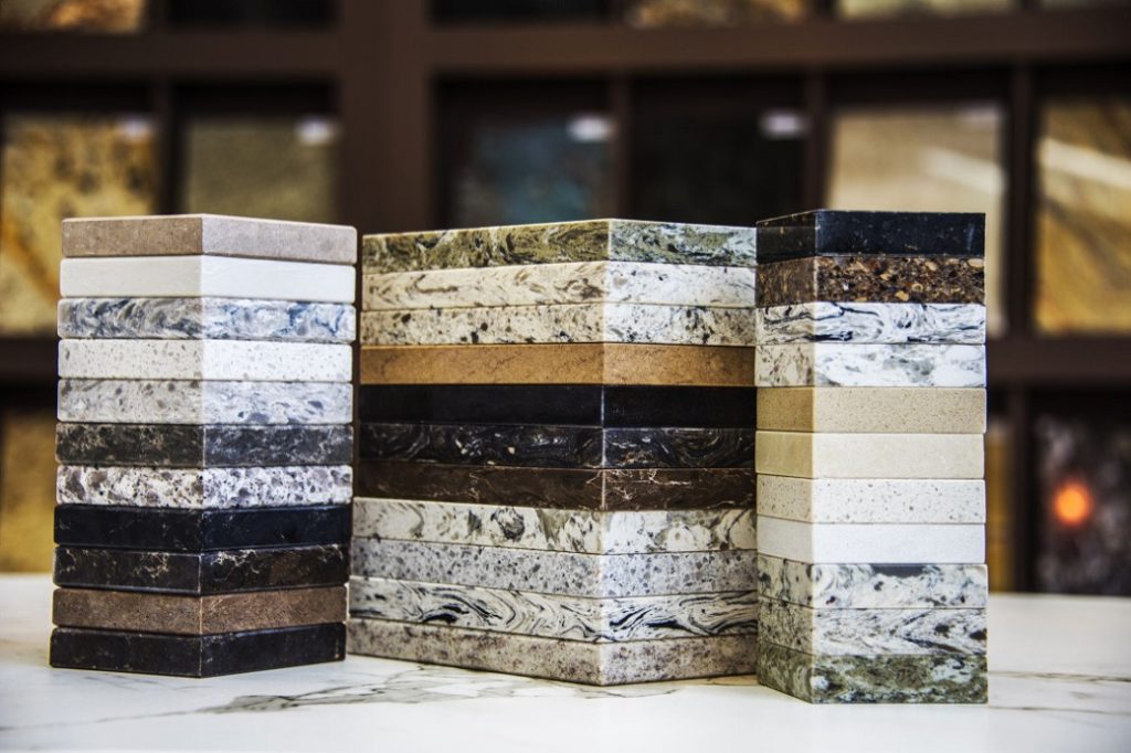 Three stacks of various kitchen countertop material samples in different colours and patterns