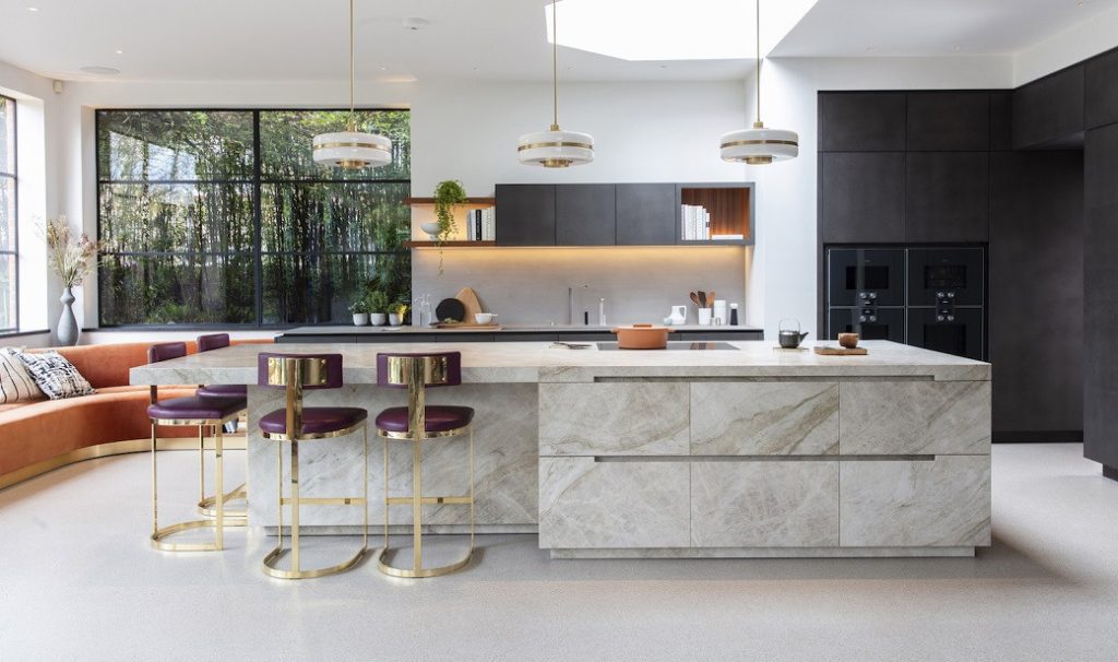 Kitchen island with stone finish and three purple stools with gold frames in bright kitchen
