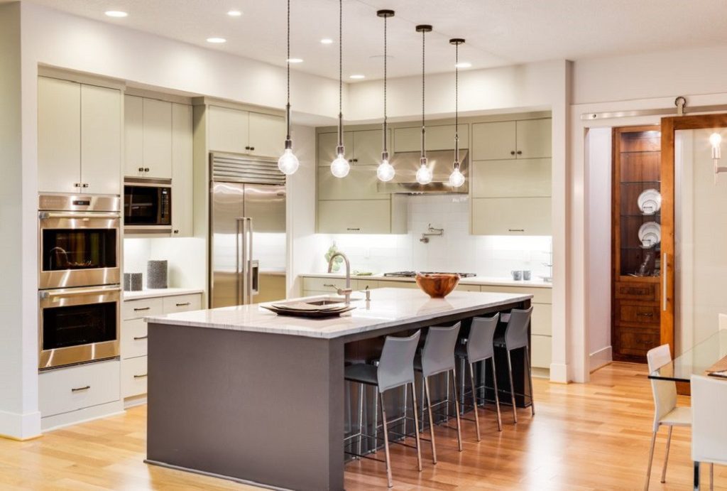 Spacious kitchen with large island, pendant lights, and stainless steel appliances