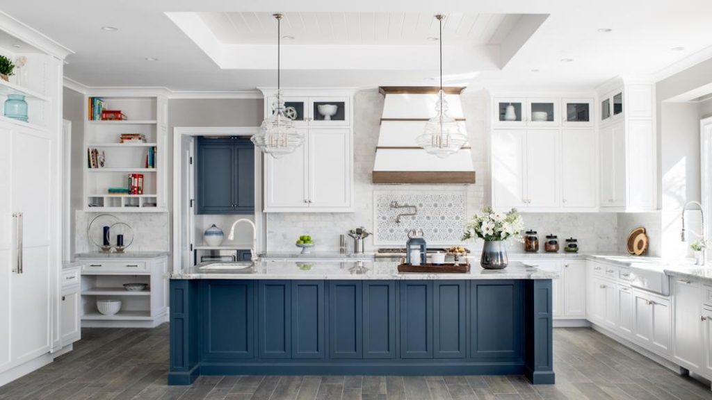 Spacious kitchen with blue island, white cabinetry, pendant lights and stone countertops