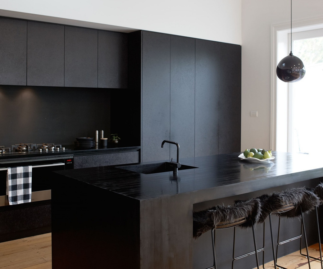 Modern kitchen with matte black cabinets, black countertop island with sink, fur-covered bar stools, and a hanging black pend