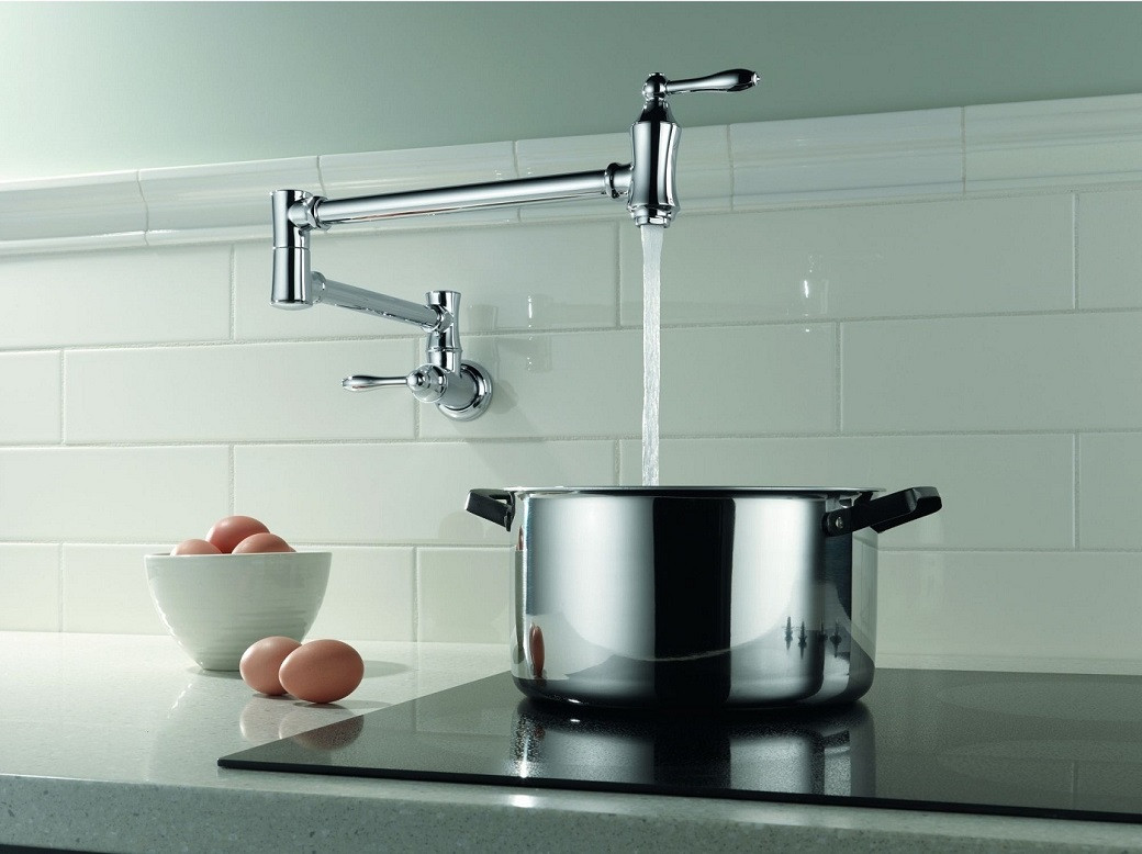 Chrome pot filler faucet above a shiny stainless steel pot on a black stovetop, with a bowl of brown eggs on the side.