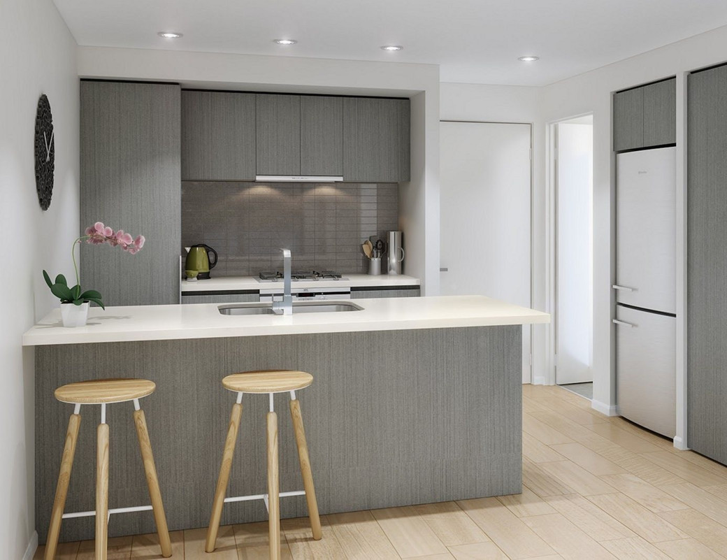 Small modern kitchen with grey cabinets, white countertop island with sink, two wooden stools, and wooden floor.