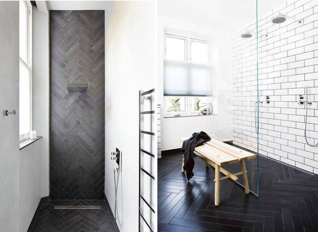 Modern bathroom with black herringbone tiles on shower wall and floor, white subway tiles on another wall, wooden bench.