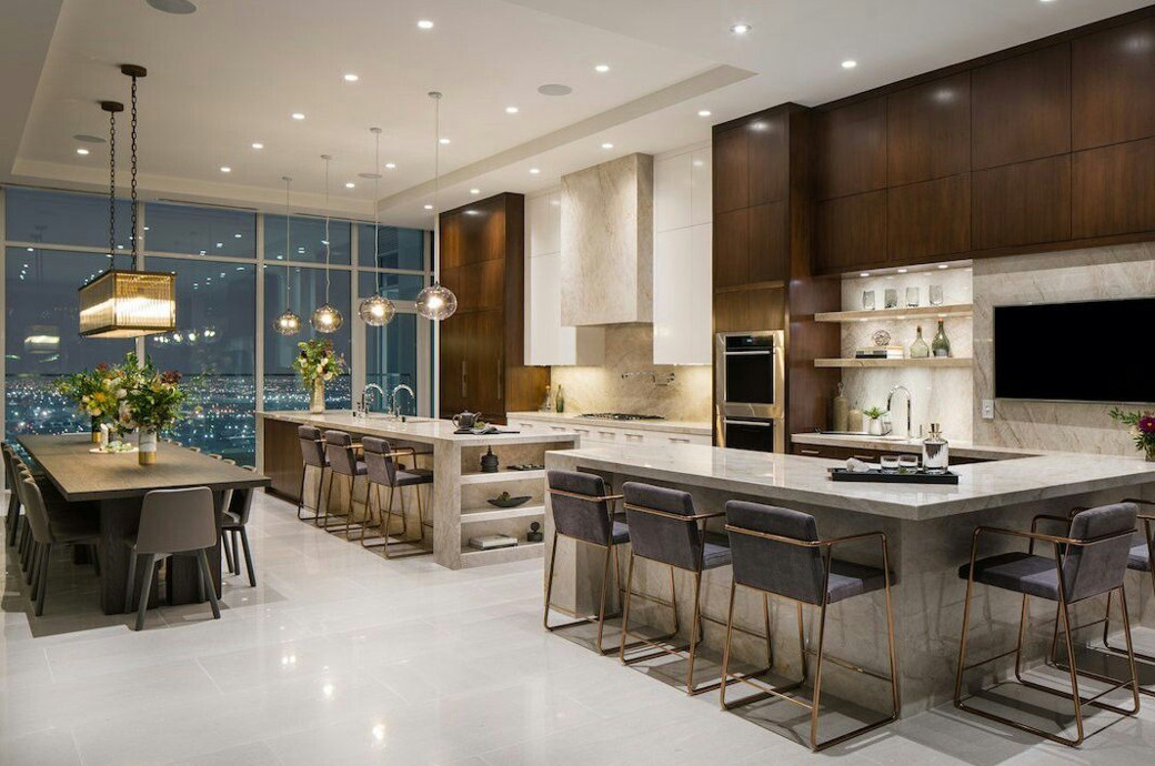 Spacious luxury penthouse kitchen with marble countertops, dark wood cabinets, dining table, pendant lights, and city view wi