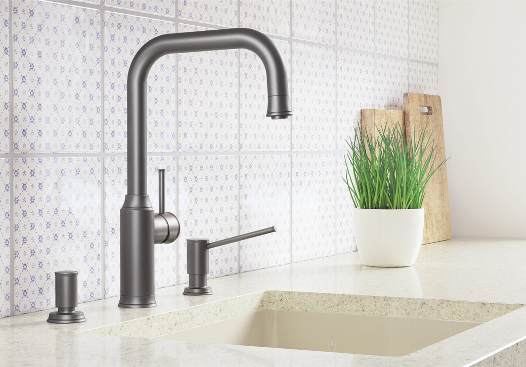 Modern kitchen sink area with matte black faucet, patterned white tiles, potted green plant, and wooden cutting boards.
