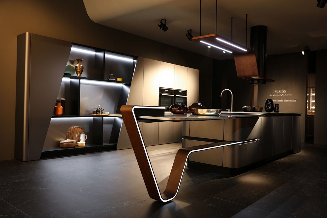 Ultra modern kitchen with sleek island, integrated sink, built-in oven, backlit shelves, and minimalist decor.