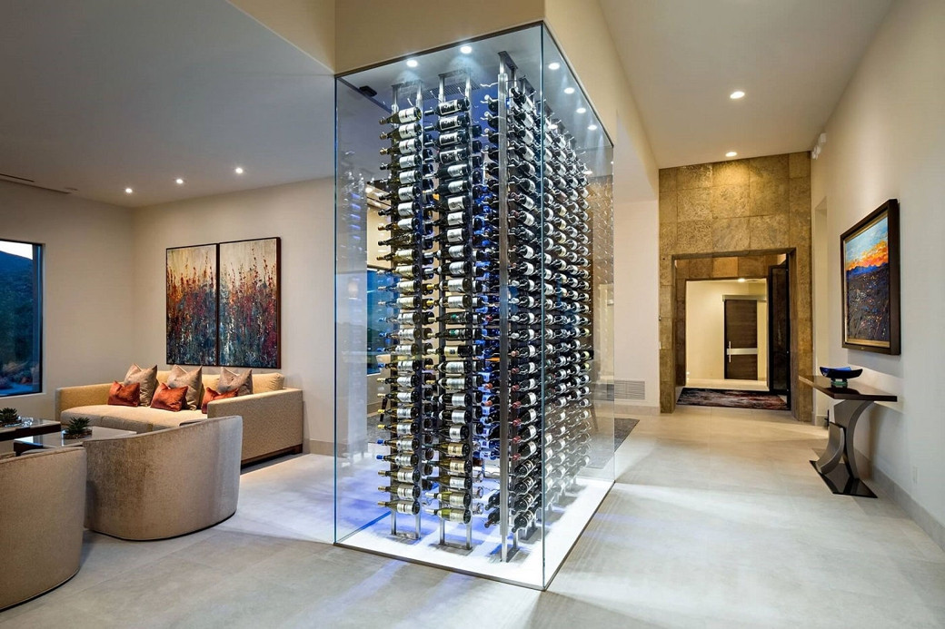 Modern living space with a glass-enclosed wine cellar at the centre and a beige sofa set next to it.