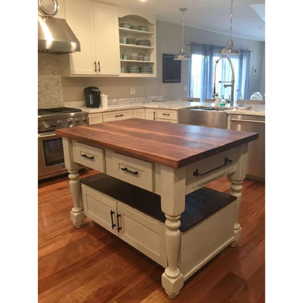 Kitchen island with a dark wooden top, cream base, drawers, cabinets, and wood flooring in a modern kitchen.