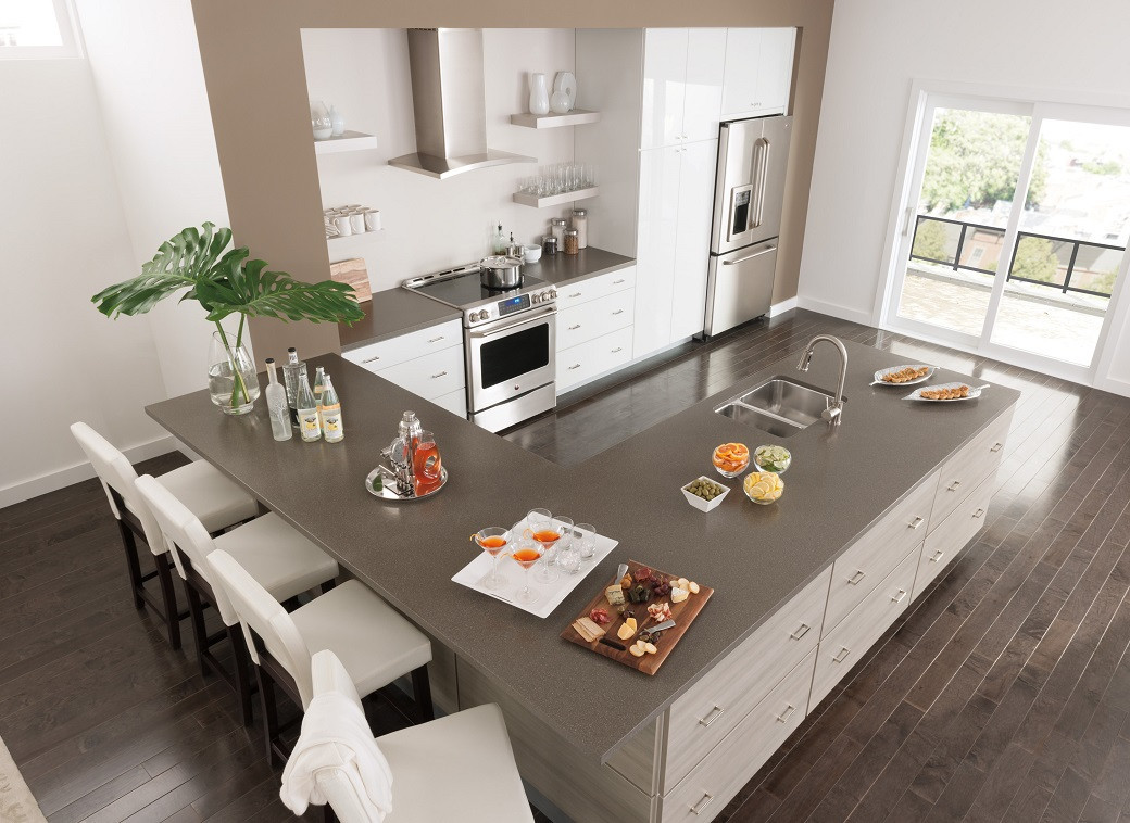 Modern kitchen with a large U-shaped island, white cabinets, stainless steel appliances, and four white bar stools.