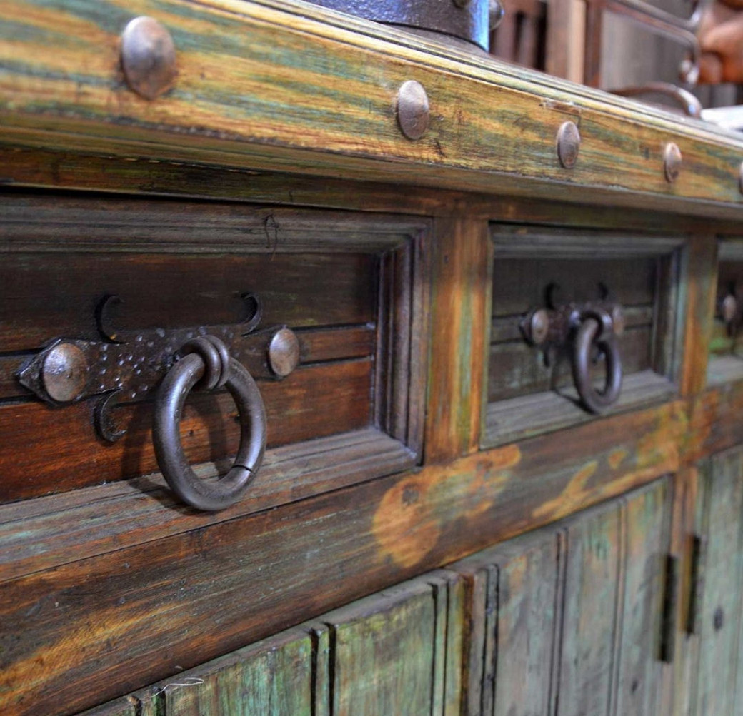 Close-up of rustic wooden kitchen cabinets with round metal ring handles and decorative metal studs.