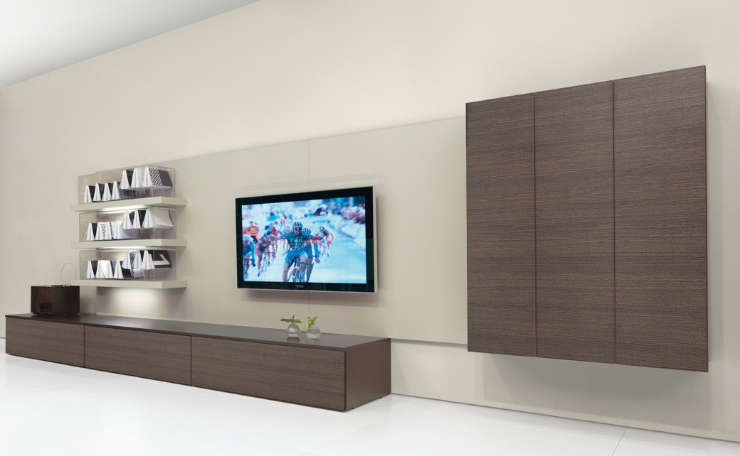 Modern living room with a custom brown wood TV unit, wall-mounted shelves, and a flat-screen TV showing a cycling race.