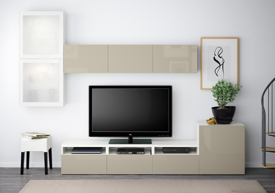 Modern beige and white custom TV unit with a flat-screen TV, decorative plant, framed art, and a small stool with books.