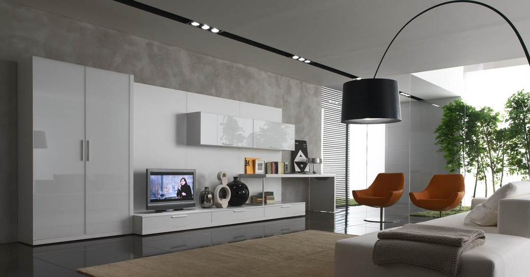 Modern living room with a white glossy custom TV unit, wall cabinets, two brown chairs, and a black arc floor lamp.