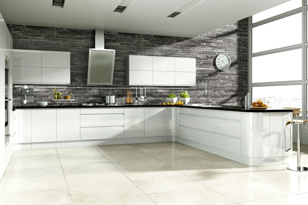Modern white kitchen with glossy cabinets, black countertops, stone tile floor, and large windows.