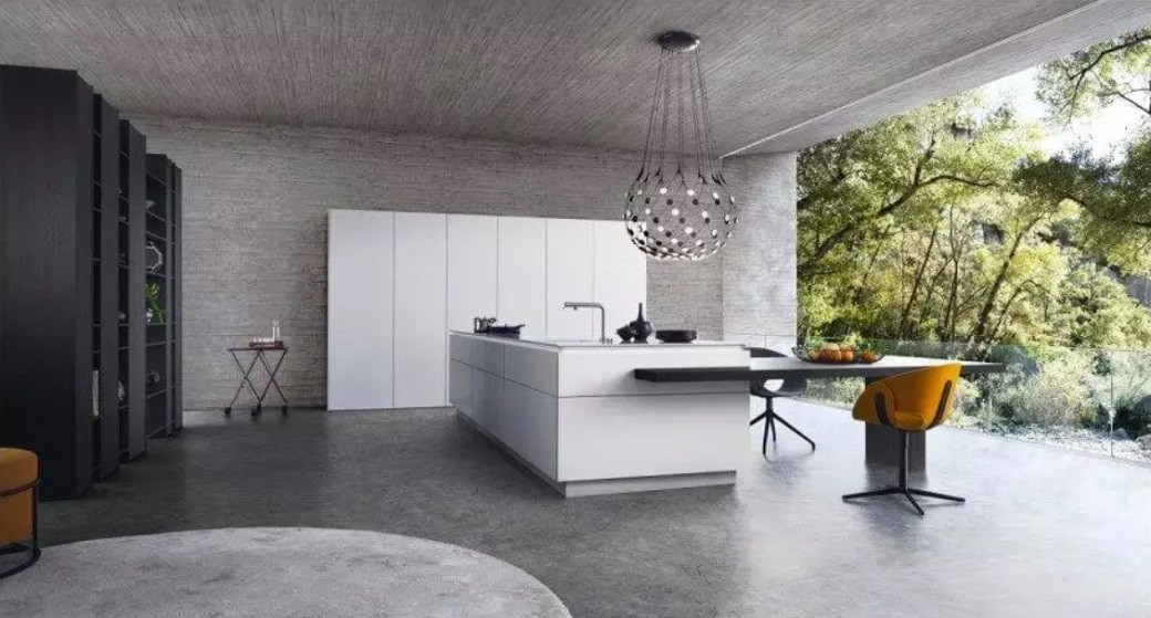 Modern kitchen with a large white island, black shelving, pendant light, and large glass window overlooking trees.