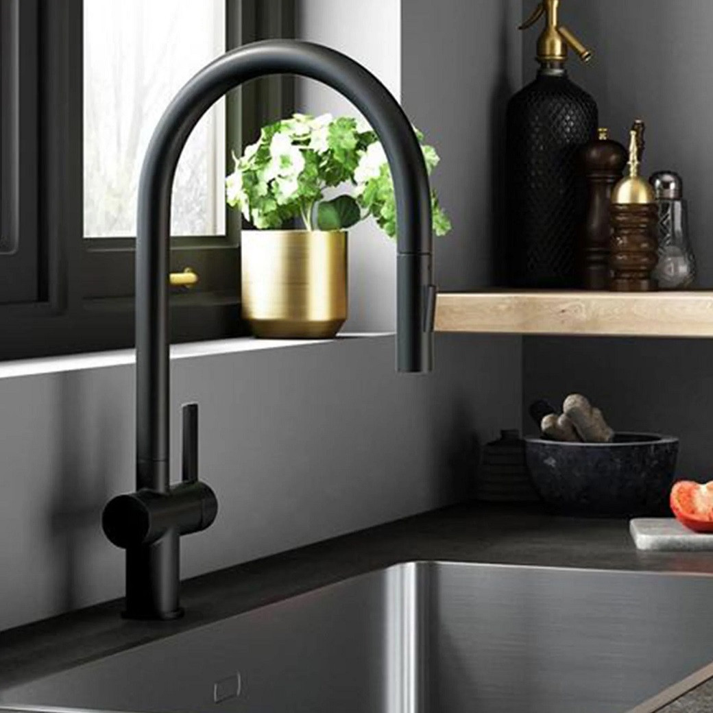Modern black kitchen tap over stainless steel sink, beside a gold pot with green plant and wooden shelf with spice containers
