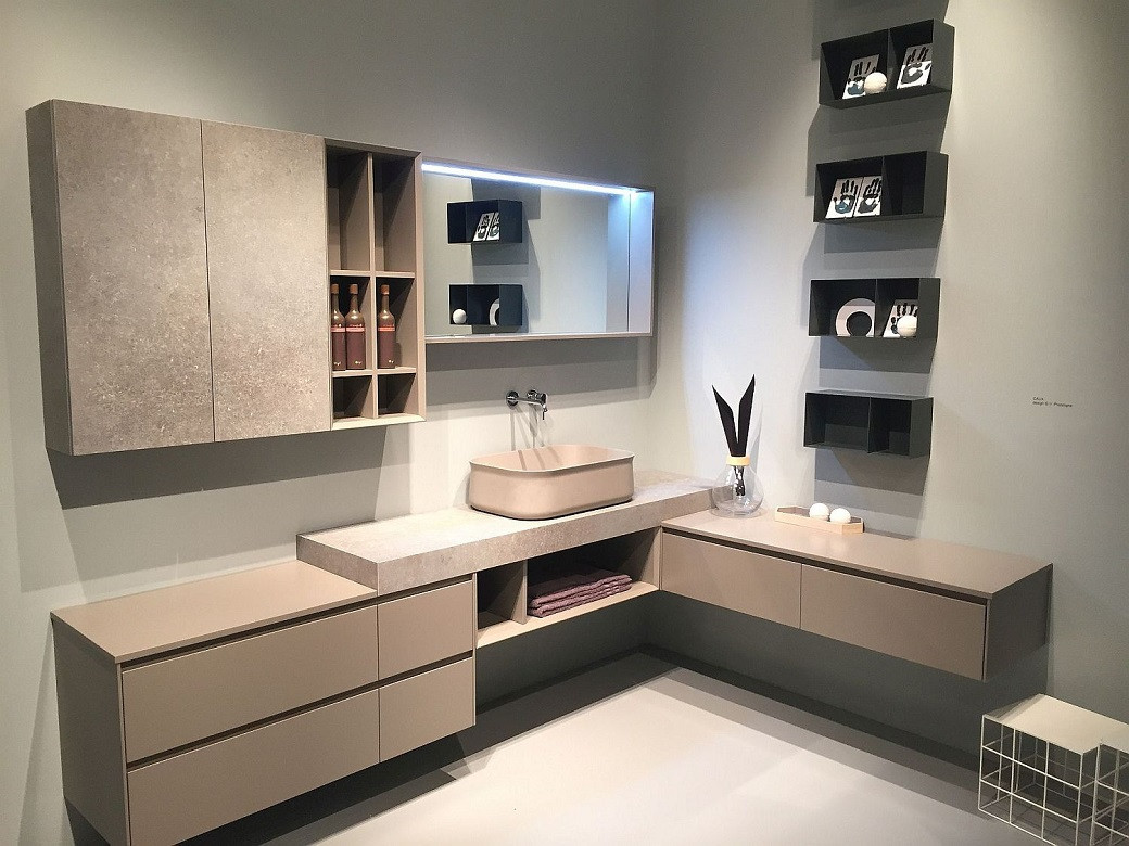 Modern bathroom vanity setup with beige wall units, integrated sink, open shelves with towels and decorative items, and a lig