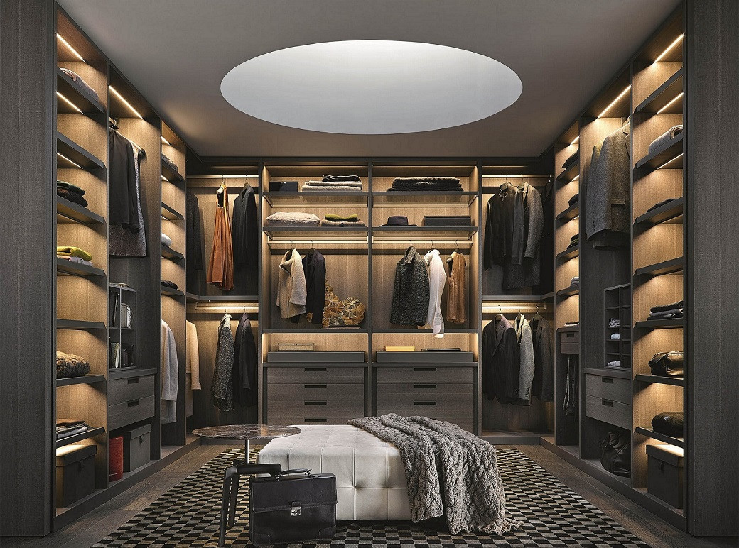 Walk-in closet with dark wood shelves, clothes hanging, folded items, a white tufted bench, and circular ceiling light.